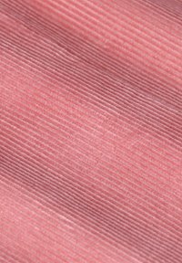 Tissu en velours côtelé rose texturé avec des côtes verticales. La surface semble douce et lisse, affichant une couleur et un motif uniformes.