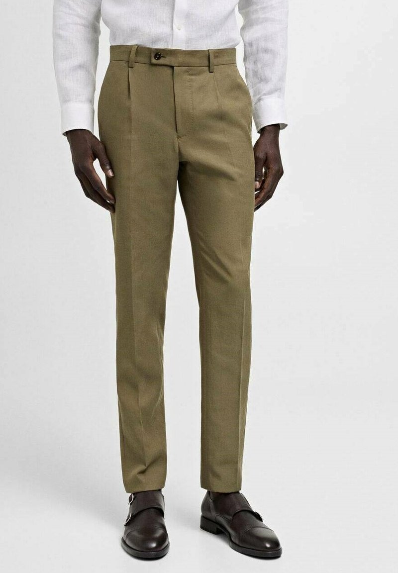 Olive green tailored trousers with a smooth texture, featuring a comfortable waistband and front pleats, paired with dark brown shoes.