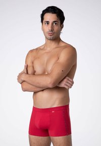 Boxer briefs rossi in cotone con un design aderente, caratterizzati da una vita piatta e un dettaglio a contrasto sulle cuciture laterali. Texture morbida, branding minimal.