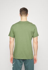 Camiseta de algodón verde oliva con manga corta, cuello redondo y un ajuste relajado, que presenta un diseño liso y una textura suave.