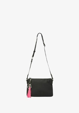 Bolso bandolera sintético negro con adorno de borla rosa, correa ajustable y logo en relieve. Textura lisa, forma rectangular.
