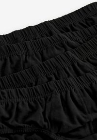 Schwarze Baumwollunterwäsche mit weicher Textur, ausgestattet mit elastischen Bündchen und gerafften Details. Drei Paar horizontal gestapelt.