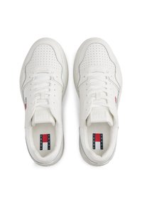 Baskets blanches avec un design perforé, tige en synthétique, lacets plats et un logo sur le côté. La semelle extérieure présente un motif de texture antidérapante.