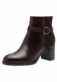 Bottine marron avec un bout en cuir lisse et un tige en daim. Elle présente une bande assortie accentuée d'une boucle en métal et un talon épais.