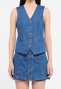 Denim set bestående av en ärmlös väst med V-ringning och fem bruna knappar, samt en matchande kjol med knappstängning fram.