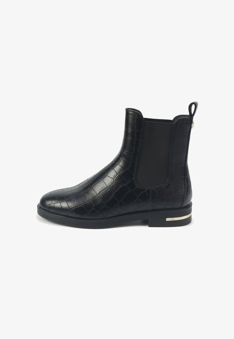 Zwarte enkellaars met krokodillenstructuur, elastische zijpaneel, trekhaak bij de hiel en een lage blokhak met een klein metallic detail.