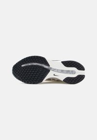 Nike shoe outsole with black rubber tread pattern, the midsole in white with a textured finish, featuring accents of grey and a visible logo.