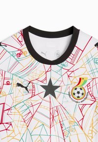 Maillot de football blanc avec motifs géométriques multicolores, étoile noire au centre, logo Puma sur la poitrine gauche et écusson de l'Association de football du Ghana sur la poitrine droite.