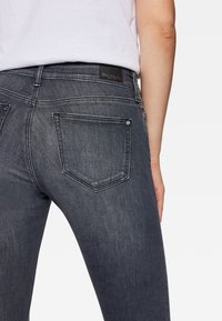 Mörkgrå jeans med en kroppsnära passform, som har två bakfickor och subtila sömdetaljer. Midjan har en varumärkesetikett.