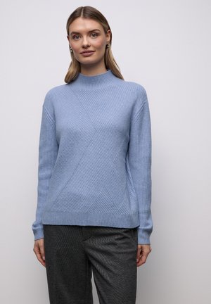 Pull en tricot bleu clair avec un col montant, présentant un motif texturé de lignes diagonales. Les manches sont longues et la coupe est décontractée.