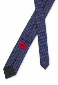 Navy blue tie featuring a geometric pattern in lighter shades, with a black lining and red logo label marked "HUGO, Made in Italy."