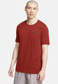 Czerwona, krótkosleeve koszulka sportowa w kratkę, okrągły dekolt i czarne logo na piersi; wykonana z teksturowanego, oddychającego materiału.