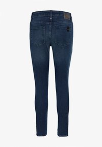 Jeans ajustados de un azul oscuro con una textura suave, dos bolsillos traseros y un parche de cuero en la cinturilla. Diseño clásico de denim.