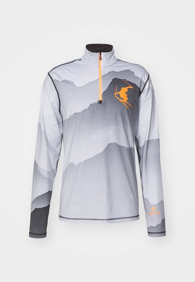 Kerge hall pikakäistega topp mägimustriga. Omab pooltõmblukuga kaelust, oranži suusataja siluetti ja musti aktsente käistel.