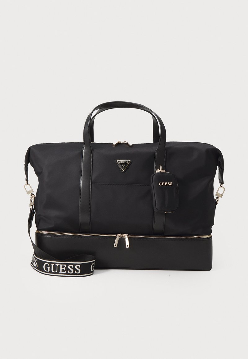 Sort nylon tote taske med sorte læderdetaljer, en lynlåslomme, gyldent hardware og en aftagelig rem med "GUESS" logo.
