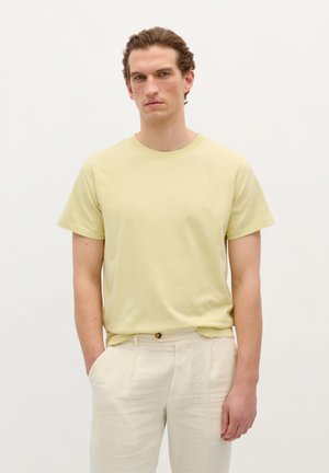 Tricou din bumbac galben deschis, cu mâneci scurte și decolteu rotund. Purtați-l cu pantaloni din in bej, plisati. Design simplu, fără modele.