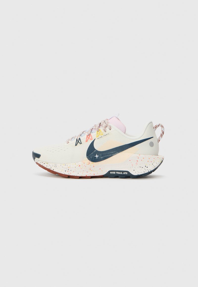 Basket de course légère en crème, avec un swoosh marine, une semelle mouchetée, des lacets multicolores et une tige texturée pour la respirabilité.