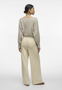 Lichtbeige gebreide trui met een relaxte pasvorm, brede mouwen, gecombineerd met crèmekleurige wijde broek met een elastische tailleband en een gladde textuur.