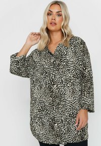 Camicia a maniche lunghe con stampa leopardata nei toni beige e nero, caratterizzata da una vestibilità ampia, un colletto e due tasche frontali.