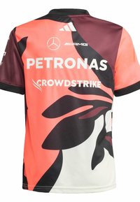 Jersey deportivo de manga corta con un diseño degradado en coral y marrón oscuro, con logotipos de patrocinadores en blanco y un cuello negro.