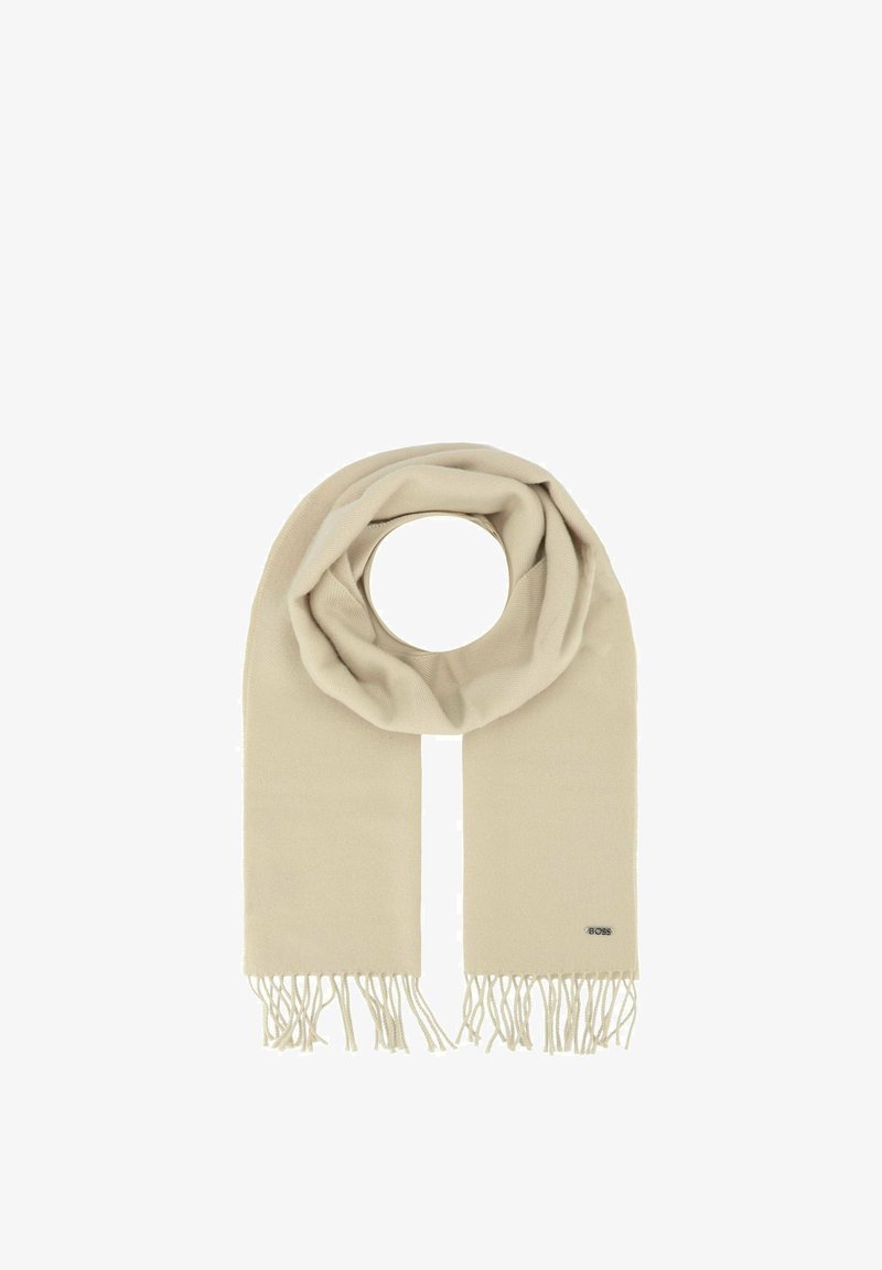 Sciarpa beige realizzata in materiale morbido con un design circolare, caratterizzata da bordi frangiati e una piccola etichetta con logo su un lato.