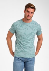 Šviesiai mėlynas trumpomis rankovėmis marškinėliai su tekstūriniu lapų raštu, apvaliu iškirptės kraštu ir mažu logotipo detaliu ant krūtinės.