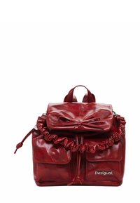 Roter Leder-Rucksack mit einem gerafften oberen Teil, zwei Fronttaschen und einem vorderen Deckel mit einer Schleife, markiert mit "Desigual". Glatte Textur, glänzende Oberfläche.