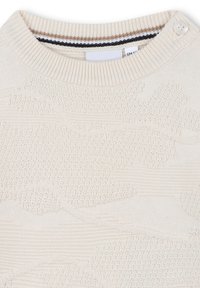 Maglione lavorato a maglia di un beige chiaro con un motivo a onda texturizzato, caratterizzato da un collo rotondo a coste e un dettaglio con bottoni sulla spalla.
