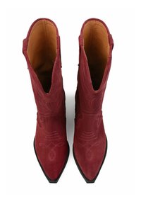 Botas de ante rojas hasta el tobillo con puntas afiladas, que presentan patrones de costura intrincados y parte superior con cortes, acentuadas por una suela negra.