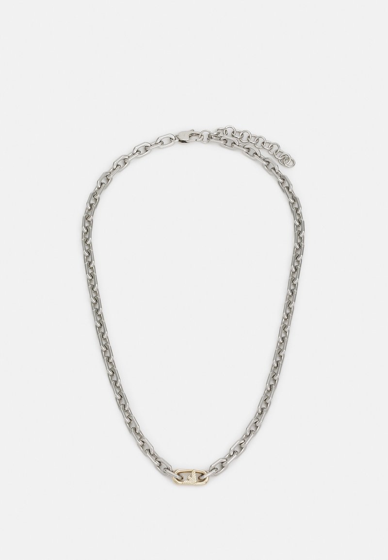Sudraba ķēde ar savstarpēji savienotiem gredzeniem un centrālu zelta akcentu. Iezīmējas ar gludu tekstūru un drošu aizdari.
