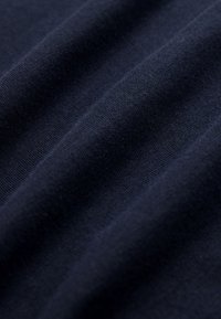 Gros plan sur un tissu tricoté bleu foncé montrant la texture et les plis doux.