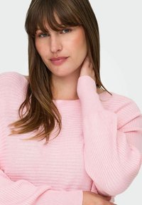 Lys rosa ribbestrikket genser med løs passform, bred halsåpning og lange ermer. Stoffet har en myk tekstur.