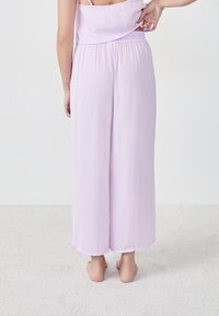 Lichtpaarse, losse wijde broek met een elastische tailleband. Zachte stof, enkel-lange zoom en een gladde textuur.