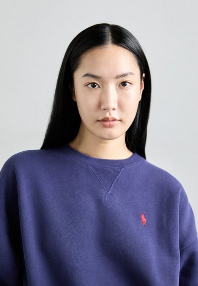 Sudadera azul marino de tejido suave, con cuello redondo y puños acanalados. Logo bordado en rojo notable en el lado izquierdo del pecho.