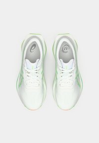 White athletic shoes with a breathable mesh upper, green accents, and grey insoles featuring branding. Designed for comfort and performance.