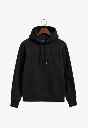 Svart hoodie med dragsko, med en präglad logotyp och text. Tillverkad av mjuk bomull, har ribbade ärmslut och fåll.