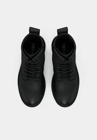 Black leather ankle boots featuring a textured finish, lace-up design, pull tab, and branding on the interior sole.