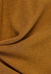 Tissu tissé de couleur moutarde chaude, présentant une texture côtelée avec des lignes fines, mettant en valeur des plis doux et une qualité de drapé.