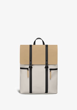 Beige og cremefarvet rygsæk med sorte lodrette stropper, to lynlåslommer foran og en top-hank, mærket Gaston Luga Stockholm.