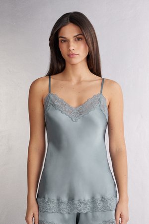 Zijde camisole in gedempt blauw met dunne bandjes. Kantafwerking langs de halslijn en zoom voegt textuur toe. Glad oppervlak en aansluitend ontwerp.