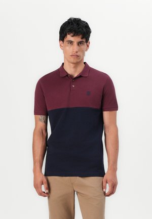Polo shirt coloré bordeaux et marine en coton. Comprend un col, trois boutons et un petit logo brodé sur la poitrine.