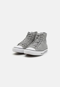 Gray canvas high-top sneakers with white rubber soles and toe caps, featuring metal eyelets and laces, with a textured upper design.
