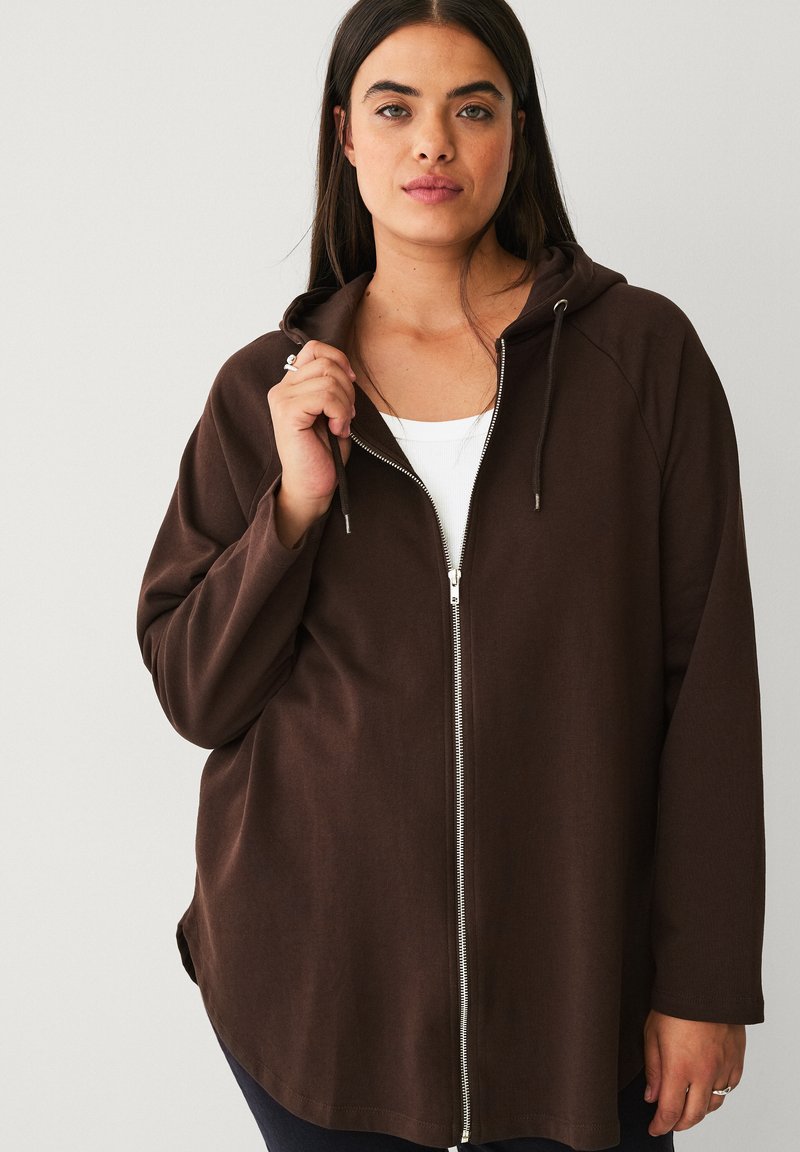 Brown zip-up hoodie with a smooth texture, adjustable drawstrings, and silver zipper. Features a relaxed fit and raglan sleeves.