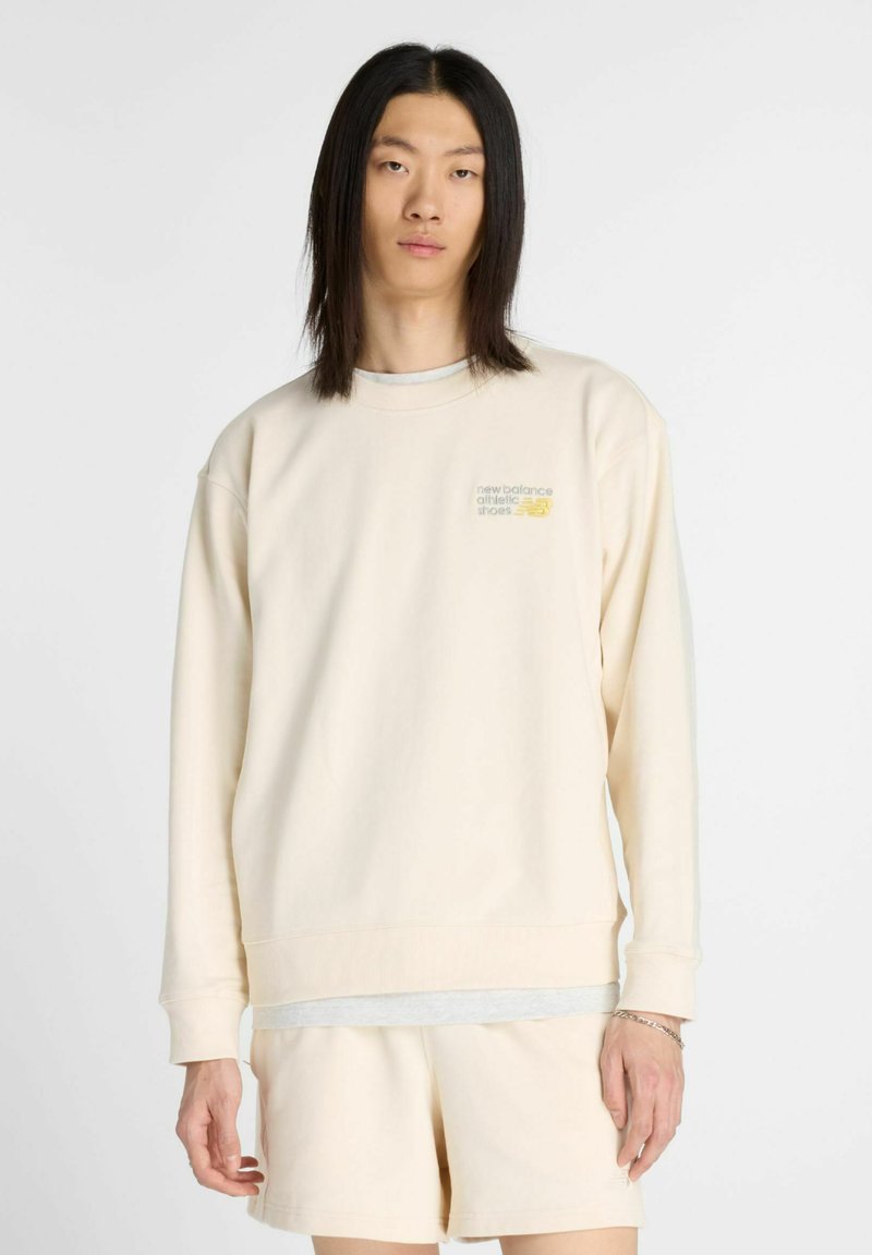 Felpa beige chiaro con maniche lunghe, polsini a coste e collo a giro. Presenta un piccolo logo stampato sul petto e una vestibilità comoda.