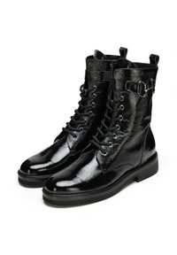Botas de cuero negro con cordones y acabado brillante, que presentan herrajes metálicos y un detalle de correa en el tobillo. Suela plana con un leve tacón.