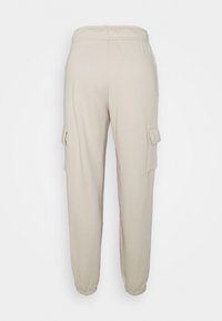 Beige cargo pants with elastic waistband, tapered cuffs, and side pockets. Made of soft fabric with a smooth texture.