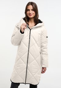 Beige gewatteerde jas met een gevlochten ruitpatroon, capuchon, zwarte voering, ritssluiting aan de voorkant en zijzakken. Zachte, gladde textuur.