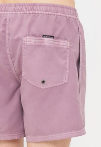 Vyrų maudymosi šortai šviesiai mauve spalvos, pagaminti iš lygaus audinio. Apskritai turi elastingą juosmenį ir nugarinį kišenę su spaudos uždarymu.