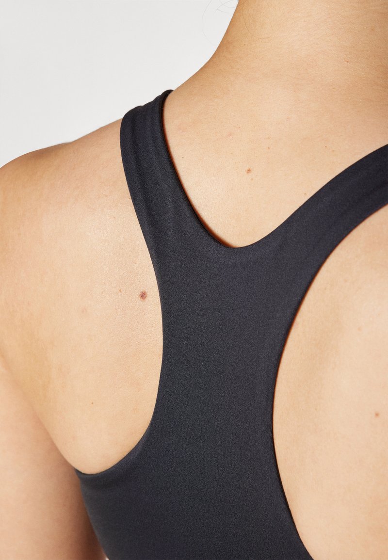 Schwarzer Sport-BH mit Racerback-Design. Glattes, dehnbares Material mit einem eleganten Finish. Nahaufnahme des Rückens, die eine nahtlose Silhouette zeigt.