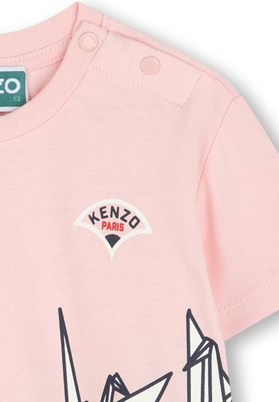 T-shirt en coton rose avec un col rond, des boutons-pressions à l'épaule et une impression graphique avec le logo "KENZO PARIS" dans des couleurs contrastées.